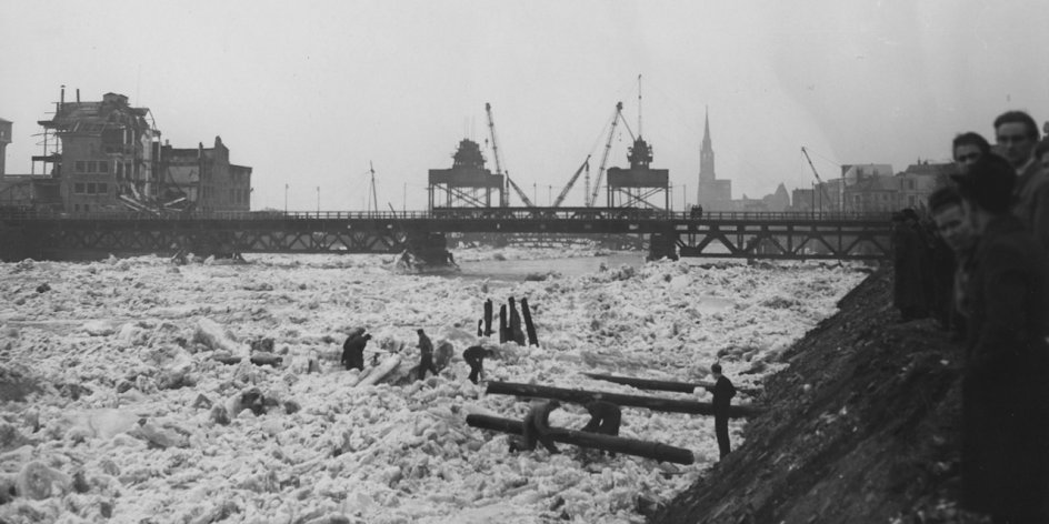 Ein Fluss voller Eistrümmer, im Hintergrund eine Brücke, Schwarz-Weiß-Fotografie; Quelle: Staatsarchiv Bremen